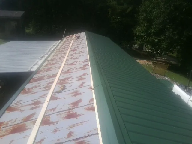 Old rusted panels beside newly installed green metal roofing — Wind Damage Roof Repair by Roofing Brothers in New Egypt
