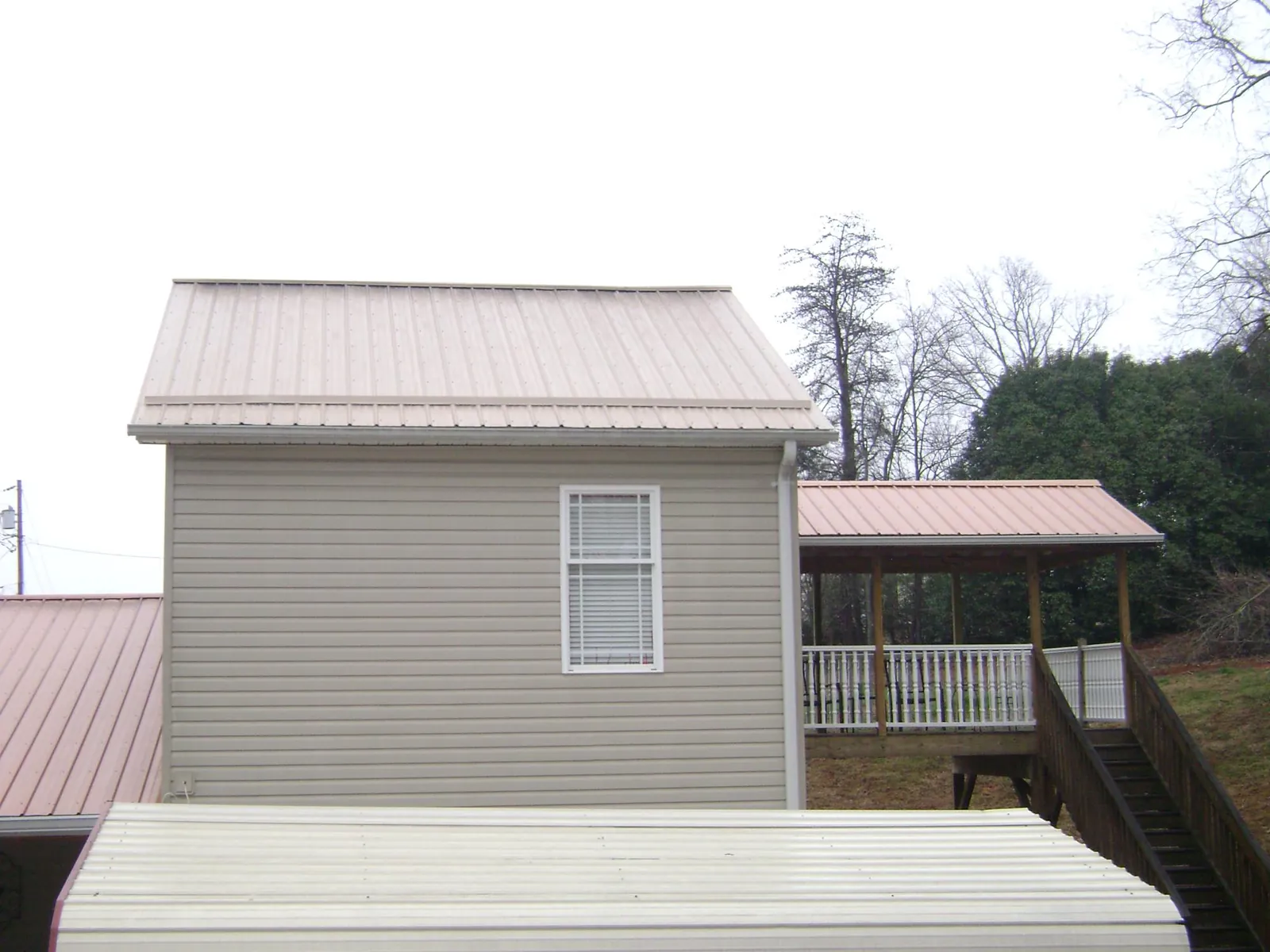 Tan metal roofs on a two story addition and attached porch, from a Roof Replacement job in New Egypt